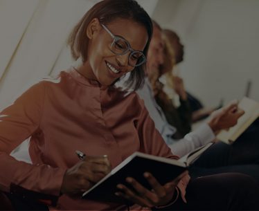 smiling-african-businesswoman-taking-notes-during-Q7REVA5