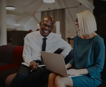 two-coworkers-laughing-together-while-sitting-on-QLXRTUE